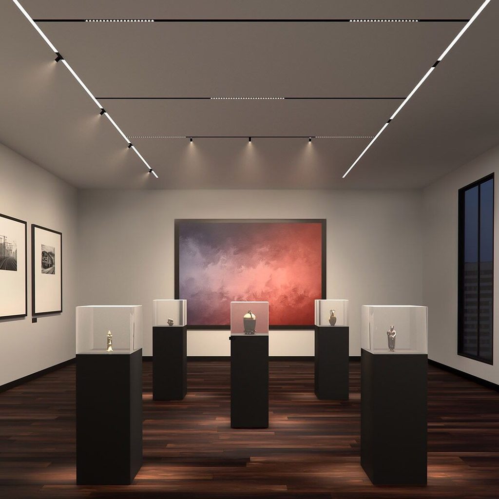 Đèn ray nam châm trong không gian gallery được bố trí để tạo vùng sáng tập trung cho tranh và các vật thể trưng bày, giúp kiểm soát hướng chiếu và làm nổi bật điểm nhấn thị giác.